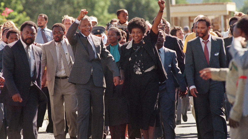 HER SLIPPER HAN UT: Mandela slapp ut av Victor Verster Prison i Paarl 11. februar 1990. Her kommer han ut fra den 11. februar 1990. Hendelsen, hvor han og Winnie Mandela gikk ut av fengselet hånd i hånd ble vist på fjernsyn over hele verden, og tusenvis av mennesker var samlet rundt porten. Foto: Alexander Joe / AFP, SCANPIX NTB